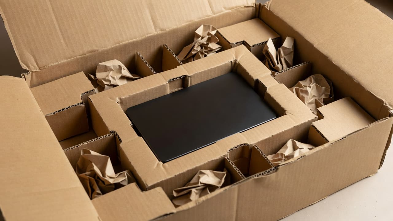 A cardboard container displays items fixed firmly with custom-cut structural inserts. Clean void fill fills the remaining gaps to ensure total stability, highlighting a professional and highly efficient protective packing method.