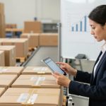 Woman reviewing packaging costs on a tablet in a warehouse.