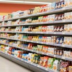 Colorful products are stacked neatly on a supermarket end cap beside shopping baskets.